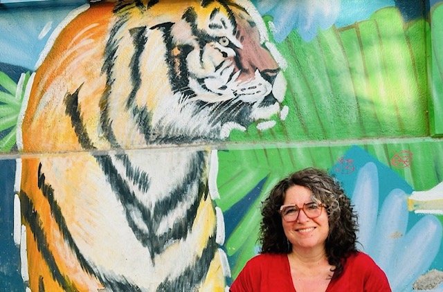 Photo of writer Rebecca Tiger with an image of a tiger in the background.